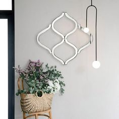 a plant is sitting on a chair in front of a wall with two lights hanging above it