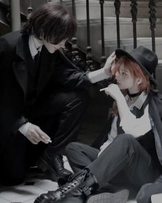 two people dressed in black and white sitting on the ground