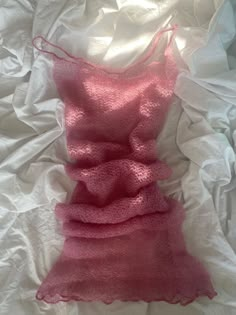 a pink dress is laying on a white sheet and it looks like something from another fabric