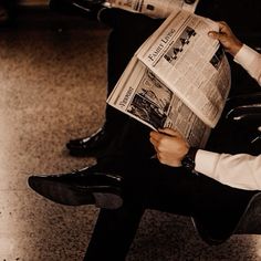 a man sitting in a chair reading a newspaper