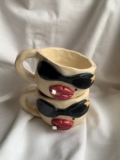 three ceramic mugs stacked on top of each other with lips painted on the sides