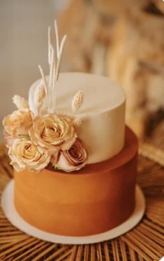 a close up of a cake with flowers on it sitting on a wicker table