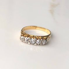 A vintage 18 carat gold five stone diamond ring. The setting holds the five cut stones up high beautifully letting them sparkle! CONDITION: Wear consistent with age and use. Please see photos for more detail. HALLMARKED 18 CARAT GOLD  BAND WIDTH: 2mm SETTING SIZE: 15mm x 4mm DIAMOND SIZE: (.05 carat) (.07 carat) (.10 carat) (.07 carat) (.05 carat) SETTING HEIGHT: 4mm RING SIZE: UK: M | US: 6 1/4 WEIGHT: 3.3G (DHZ) Cameo Bracelet, Stone Diamond Ring, Cute Engagement Rings, Gold Diamond Band, Vintage Wedding Band, Dope Jewelry, Jewelry Lookbook, Multi Stone Ring, Jewelry Inspo