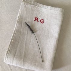 a piece of cloth with embroidered letters and a single flower on the side, sitting on top of a bed