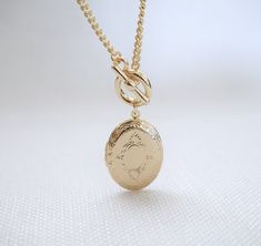 Oval Locket Toggle Necklace Details : - Oval locket to keep secret messages/photographs of your loved ones close to your heart - suspended on curb chain, finished with toggle clasp - made of 16K gold plated over brass - necklace length : 18 inches - pendant : 32 mm x 21 mm - photo compartment : 20 mm x 15 mm Gold-tone Locket Chain Necklace As Gift, Gold-tone Chain Necklace With Locket For Gift, Oval Link Toggle Necklace As Gift, Gold-tone Oval Link Toggle Necklace Gift, Gold-tone Oval Link Toggle Necklace, Gold Oval Link Toggle Necklace Gift, Gold Oval Link Toggle Necklace As Gift, Gold Toggle Necklace With Oval Links As Gift, Vintage Chain Necklace With Toggle Clasp As Gift