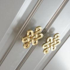 two pairs of gold earrings sitting on top of a white door frame with knot design