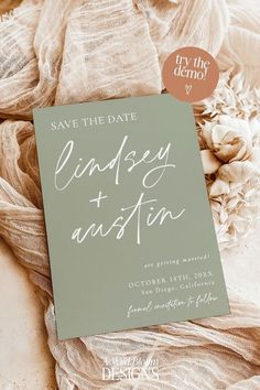 save the date cards are sitting on top of some cloths and fabric, with an envelope