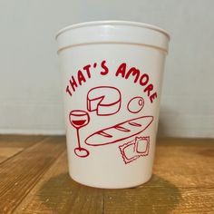 a white cup with red writing on it that says, that's amore