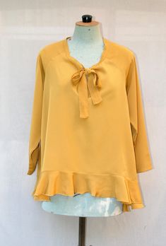 The  blouse is made of mustard yellow polyester crepe fabric. The shape blouses is wide and asymmetric (shorter in the front) and has a large ruffle on the blouse edge. You can tie the neckline or leave it open. Blouse length: Back: 70cm - Front: 50 cm Size: Fr  One size fit (38 to 42) Composition: 100% Polyester Care of clothing: Wash 30oC - Cool iron - Dry cleaning https://www.etsy.com/fr/shop/VLbasics?ref=seller-platform-mcnav Flowy Yellow Blouse For Fall, Chic Mustard Blouse For Fall, Yellow Ruffled Long Sleeve Blouse, Chic Tie Neck Flowy Blouse, Yellow Long Sleeve Blouse With Ruffles, Chic Mustard Top For Brunch, Chic Yellow Blouse, Yellow V-neck Ruffle Blouse, Flowy Yellow Blouse For Brunch