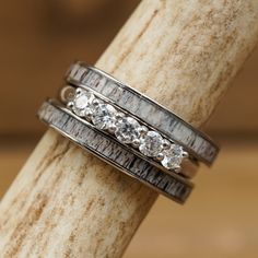 three wedding rings sitting on top of a piece of wood with diamonds in the middle