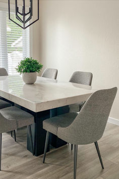 a dining room table with chairs and a potted plant in the center on top