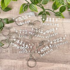 three clear key chains sitting on top of a wooden table next to some green leaves