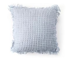 a light blue pillow with fringes on the front and back, against a white background