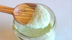 a wooden spoon is in a jar filled with green liquid and white stuff on it