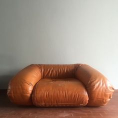 a brown leather chair sitting on top of a brick floor next to a white wall