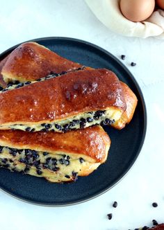 two blueberry pancakes on a plate with an egg in the background