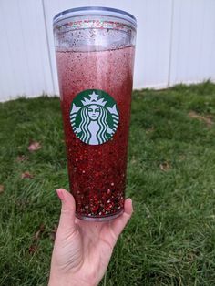 someone holding up a starbucks cup with red liquid and sprinkles on it