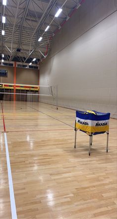 an indoor volleyball court with hard wood flooring and lights on the ceiling are empty