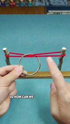 two hands are holding the end of a piece of string and another hand is pointing at it