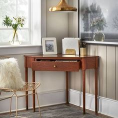 a room with a desk, chair and pictures on the wall next to a window