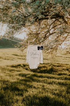 a baby's bodysuit hanging from a clothes line in the middle of a field