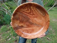 a woman holding a large wooden bowl in her hands