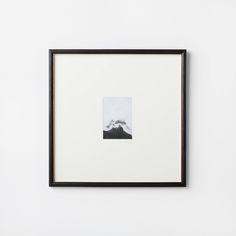 a black and white photo hanging on the wall next to a framed art print with mountains in the background