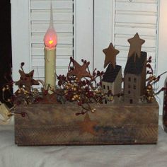 a candle is lit in front of a wooden box with houses and stars on it