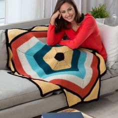 a woman sitting on a couch holding a crocheted blanket