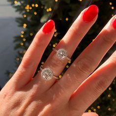 a woman's hand with two rings on it and a christmas tree in the background