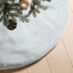 a christmas tree with ornaments hanging from it's branches on a round white table