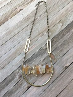 Fabulous! This delicate yet substantial stick bead bar necklace is done in genuine semi-precious citrine stones. These sparkly gold stones are so beautiful and they are shimmery in the light. This stone is so unique and beautiful. The chain has a few funky brass shapes and is attached to the bar on wire. Below it is a gold metal U that seems to be holding the bar in place.  There is a matching pair of earrings available: https://etsy.me/2Td9toT My jewelry is all handmade, so no two pieces will e Artisan Brass Necklaces With Natural Stones, Gold Artisan Multi-stone Necklace, Vintage Brass Necklace With Natural Stones, Gold Multi-strand Crystal Necklaces With Natural Stones, Gemstone Bar Necklace, Bead Bar Necklace, Stone Bar, Bead Bar, Stone Beaded Necklace