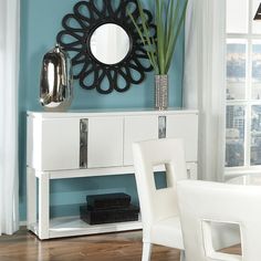 a white table and chairs with a mirror on the wall above it in front of a window