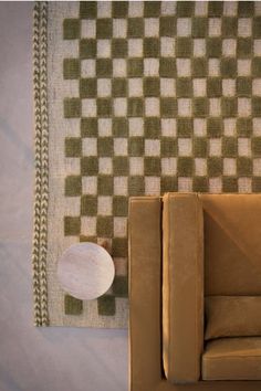 a brown couch sitting next to a rug on top of a white and green floor