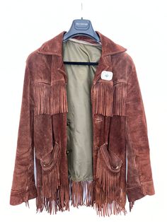 Elevate your Western style with this vintage fringe coat made of soft suede in a rich brown color. The coat features an Aztec-inspired turquoise pin, adding a pop of color to the overall design. The coat is tailored to a regular fit and comes in size M, perfect for men who want to rock the classic Western look. This coat is made of high-quality materials, with the outer shell crafted from suede and the lining made of leather. It also features fringe accents that add a touch of movement and texture to the coat. Perfect for everyday wear or special occasions, this vintage Western coat is sure to make a statement. Purchased vintage, worn with love, excellent condition.  Missing the lining, but has a full zipper to add in one!  Thick, high quality brushed chocolate brown suede, with an added b Vintage Brown Fringed Outerwear, Vintage Brown Fringe Outerwear, Fringe Coat, Fringe Coats, Vintage Chocolate, Vintage Fringe, Men Suede, Western Look, Coat Vintage