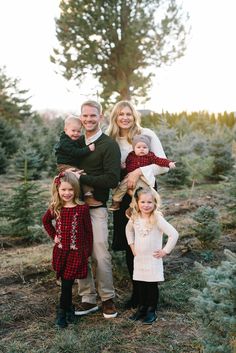 a family standing in the middle of a christmas tree farm with their arms around each other