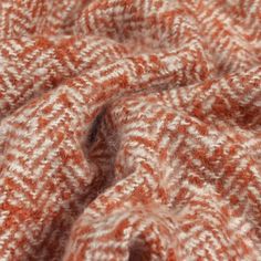 an orange and white knitted blanket is shown in this close up photo, with the texture