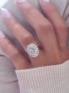 a woman's hand with a diamond ring on her finger and white nail polish