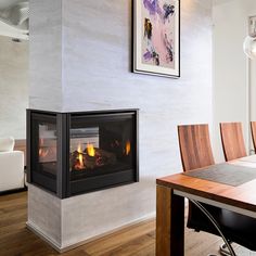 a room with a table, chairs and a fire place in the middle of it