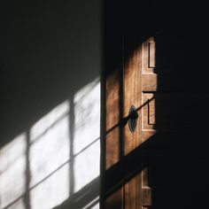 an open door with the light coming through it's glass panes and casting a shadow on the wall