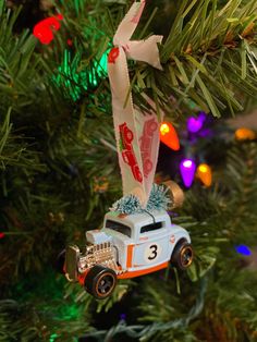 an ornament hanging from a christmas tree with lights in the background and cars on it