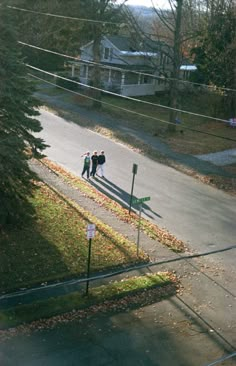 two people are walking down the street in front of some trees and power lines with houses behind them