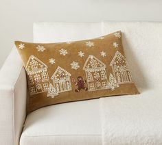 a brown pillow with gingerbread houses and snowflakes on it sitting on a white couch