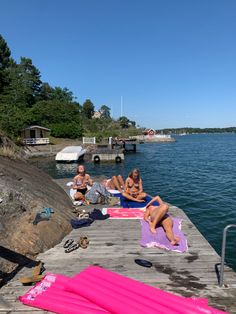 some people are sitting on the dock by the water with towels and blankets around them