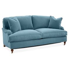 a blue couch with two pillows on the back and one pillow in the middle, against a white background