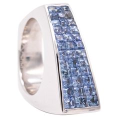 A Geometric cocktail ring with Ceylon Blue Sapphires. An aerodynamic bold piece made in Italy, with an asymmetric shape. It was crafted in solid white gold of 18 karats, with highly polished surfaces. Is set on top with calibrated invisible settings of 36 French squared step cuts of natural vivid Ceylon blue sapphires, with a total weight of 2.52 carats. Have a total weight of 22.8 grams and the actual size is 6, sizable. The top view measures are 9 mm by 23 mm. Stamped, with the Italian assay c