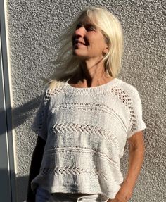 an older woman standing in front of a white wall