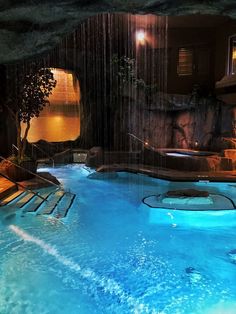 an indoor swimming pool with waterfall and lounge chairs