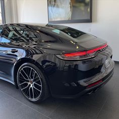 a black sports car parked in a showroom with large windows and chrome rims