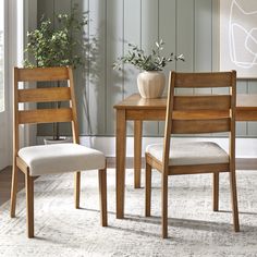 two wooden chairs sitting next to each other in front of a table with a potted plant on it